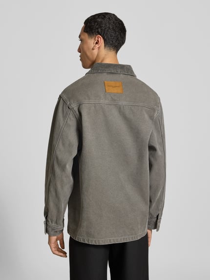 Männermodel trägt Strickjacke aus Alpaka Wolle von Officine Générale im Used Look, Denim-Optik, grau, Ganzkörperansicht Rückansicht.