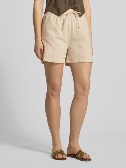 Kobiece model prezentuje Regular Fit Bermudas aus reiner Baumwolle Modell 'TIZANA' od Only, kolor jasnobeżowy, wpuszczane kieszenie, wykończenie: cieniowana przędza, krój regular fit, tunel, elastyczny ściągacz, materiał: bawełna, całkowity przód.