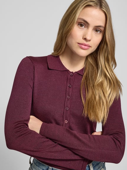 Vrouwenmodel draagt bordeauxrood Slim Fit Langarmshirt aus Lyocell-Baumwoll-Mix Modell 'FLURA LUREX' van Selected Femme, glanzend uni, knoopsluiting, polo-, lange mouwen, ribboorden, gebreide textuur. Nahaufnahme bovenlichaam.