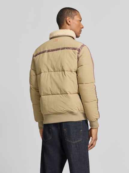 Männermodel trägt Bomberjacke mit Teddykragen TEDDY PUFFER JACKET von SCOTCH & SODA in Beige mit Struktur, Rückenansicht, Ganzkörperansicht Rückansicht.