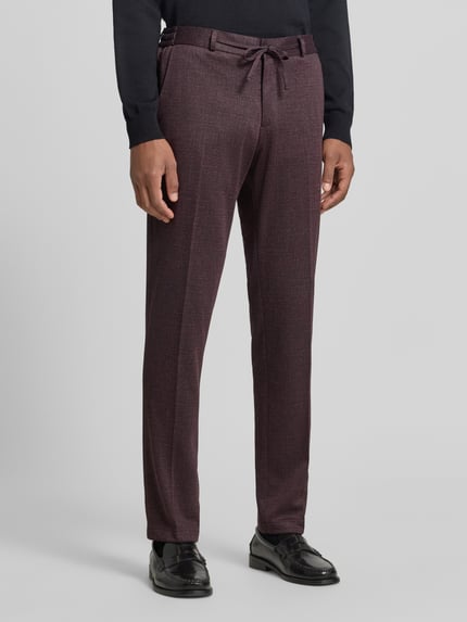 Mężczyznamodel nosi bordowe spodnie materiałowe Straight Fit Stoffhose mit Tunnelzug Modell 'Sparta' von Zuitable, wpuszczane kieszenie, zakładki w pasie, szlufki, szerokość w rozmiarze 50: 43 cm, długość wewnętrzna nogawki w rozmiarze 50: 82 cm, widok całej sylwetki z przodu.