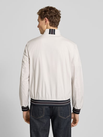 Männermodel trägt blouson mit opstaande kraag en ritssluiting van Geox in wit met zwarte details, regular fit, steekzakken, ruglengte bij maat M 68 cm, schouderbreedte 46 cm, borstwijdte 56 cm, mouwlengte 68 cm, ganzkörperansicht rückansicht