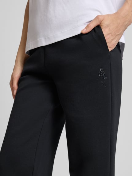 Kobiece modelka nosi Sweatpants mit elastischem Bund und Logo-Print od ARMANI EXCHANGE, czarny kolor, krój straight fit, boczne kieszenie, nahaufnahme okolicy bioder z przodu