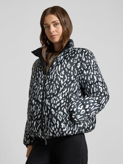 Frauenmodel trägt Regular Fit Daunenjacke mit Wendefunktion von Marc Cain, schwarz-weißes Leopardenmuster, glatte Textur, Nahaufnahme Oberkörper, Damen Daunenjacke von Marc Cain