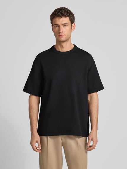 Männermodel trägt T-Shirt mit Rundhalsausschnitt Modell 'CRINKLE CREPE SPACER' von CK Calvin Klein, schwarz, Strukturmuster, Ganzkörperansicht von vorne. Material-Mix mit Modal-Anteil, Relaxed Fit, Rückenlänge bei Größe M 71 cm.