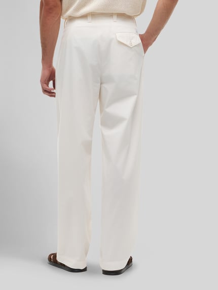 Mannenmodel draagt Loose Fit Hose mit Bundfalten van Tommy Hilfiger in effen kleuren, puur katoen, klepzak, bandplooi, loose fit, knoopsluiting, steekzakken, klepzak achter, materiaal: puur katoen. Ganzkörperansicht Rückansicht.