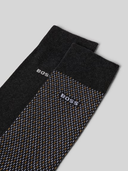 Produktfoto, Socken mit Label-Detail im 2er-Pack von BOSS aus Baumwoll-Mix mit Stretch-Anteil und elastischen Rippenbündchen, ein Paar unifarben dunkel, ein Paar mit feinem Muster in Schwarz, Weiß und Gelb.