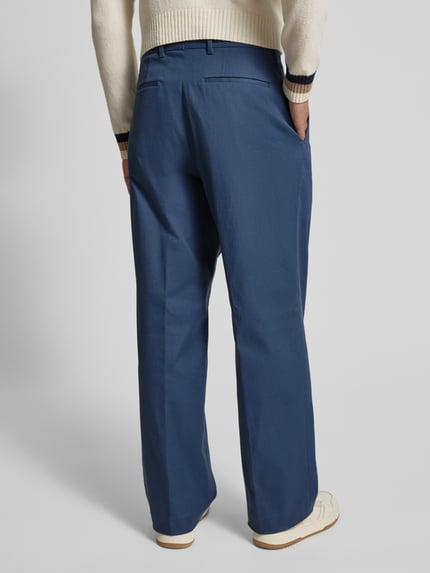 Męskimodel nosi Weite Hose aus Baumwoll-Mix Modell 'PAT' od BOSS, kolor jednolity niebieski, splot twill, spodnie z szerokimi nogawkami, zakładki w pasie, fason relaxed fit, wpuszczane kieszenie, zapięcie na haftkę i zamek, tylnie kieszenie, mieszanka bawełny, widok całej sylwetki z tyłu.