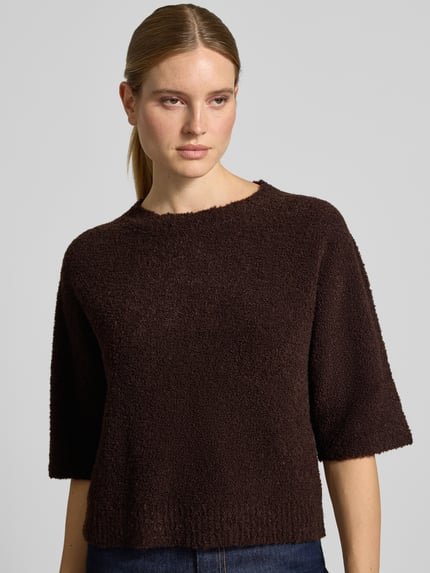 Frauenmodel trägt Oversized Pullover mit woll-Anteil von Rich & Royal in dunklem Braun, Strick-Optik, Rundhalsausschnitt, Halbarm, Material-Mix, Nahaufnahme Oberkörper.