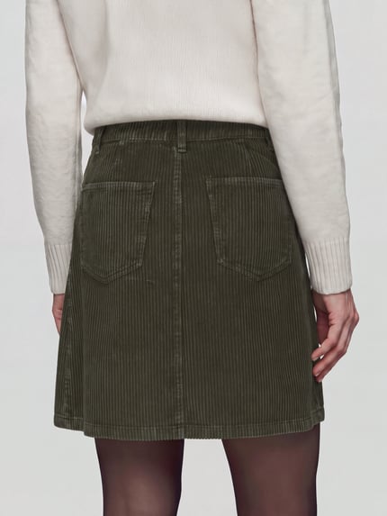 Frauenmodel trägt Rock mit Cordstruktur von S.OLIVER CASUAL in Uni-Optik mit Struktur, Gesäßtaschen und Knöpfen, Ganzkörperansicht Rückansicht.