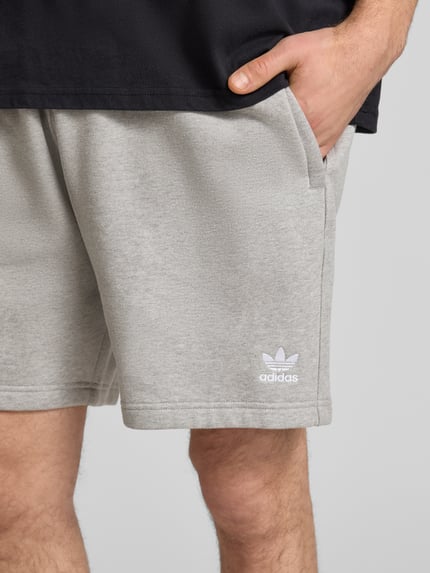 Männermodel trägt Regular Fit Sweatpants mit Logo-Stitching von adidas Originals in Hellgrau, Baumwoll-Mix, Nahaufnahme Oberschenkel.