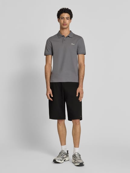 Männermodel trägt Sweatshorts mit Logo-Print von REVIEW aus schwarzem Material-Mix mit Baumwoll-Anteil, Loose-Fit, elastischer Bund, Bundweite 45 cm, Innenbeinlänge 28 cm, Ganzkörperansicht von vorne.