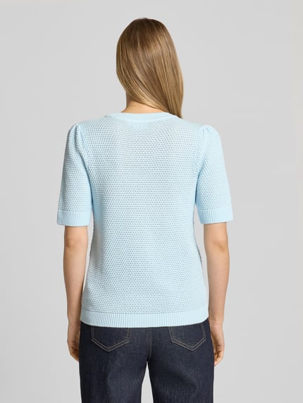 Vrouwenmodel draagt Slim Fit T-Shirt in Strick-Optik Modell 'Vidalo' van Vila in lichtblauw, fijne katoenen structuur, rugaanzicht, pure katoen, slim fit, ronde hals, ruglengte maat S 57 cm, mouwlengte maat S 27 cm.
