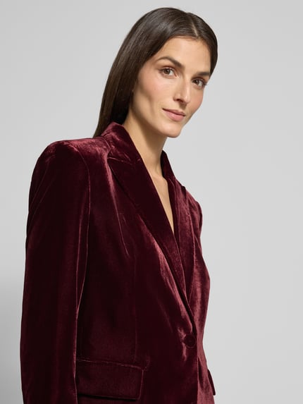 Frauenmodel trägt Regular Fit Blazer aus Samt Modell 'COMBI' von Mango, weinrot, Reverskragen, Pattentaschen, Knopfverschluss, Nahaufnahme Oberkörper.