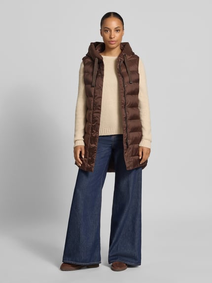 Vrouwenmodel draagt Regular Fit bodywarmer in stiksels van FUCHS SCHMITT, cappuchon met tunnelkoord, steekzakken met ritssluiting, ruglengte 77 cm, schouderbreedte 41 cm, borstwijdte 51 cm, bruine en beige tinten, structuur van doorgestikte stof, voorkant volledig zichtbaar, Ganzkörperansicht van voren.