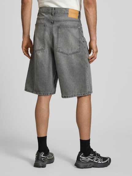 Männermodel trägt Jeansshorts im Used-Look mit Eingrifftaschen von REVIEW, graue Reine Baumwolle, Relaxed-Fit, Ganzkörperansicht Rückansicht.