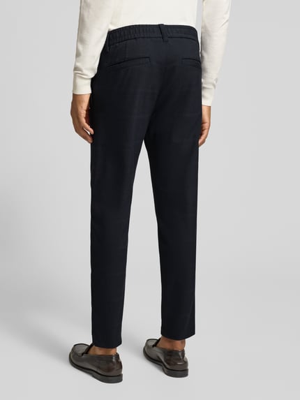 Männermodel trägt dunkelblaue Tapered Fit Chino mit Viskose-Anteil von BOSS Orange, lockerer Stoff, Ganzkörperansicht Rückansicht.