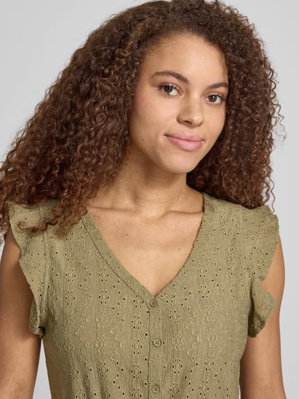 Vrouwenmodel draagt Regular Fit Jumpsuit met ajourwerk model 'LELISA' van Only, look: effen, kapmouwen, V-hals, knoopsluiting, strikceintuur. Nahaufnahme Oberkörper.