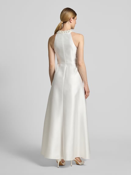 Frauenmodel trägt Maxikleid aus Satin mit Perlen von Adrianna Papell in A-Linie, cremefarben, mit Rundhalsausschnitt, Volants, Rückenreißverschluss, Rückenlänge 156 cm, Brustweite 38 cm, Ganzkörperansicht Rückansicht.