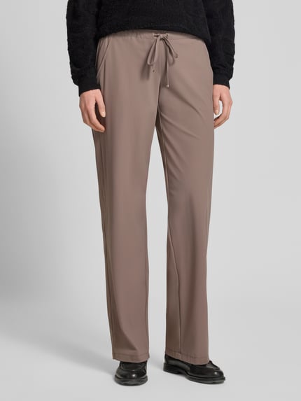 Frauenmodel trägt Straight Leg Jogpants aus Hightech Jersey Modell 'CANDICE' von Raffaello Rossi in Taupe mit Elastikbund und Schnürung, Ganzkörperansicht von vorne. Bundweite 40 cm, Innenbeinlänge 84 cm, glatte Oberfläche.
