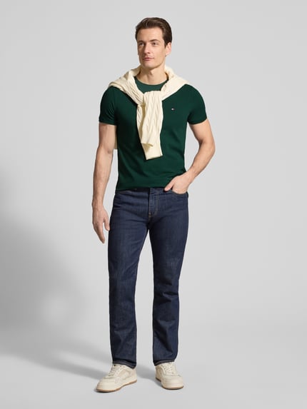 Mannelijk model draagt Slim Fit T-shirt uit katoenmix van Tommy Hilfiger, look: effen, logodetail, ronde hals, korte mouw, stretch, katoenmix. Ganzlichaamsaanzicht van voren.