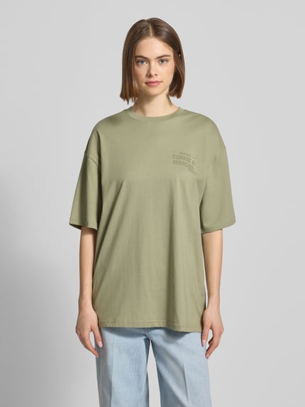 Vrouwenmodel draagt Oversized T-Shirt met Statement-Print van REVIEW in licht olijfgroen, pure katoen, oversize fit, ronde hals, voorkant, bovenlichaam close-up
