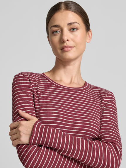 Frauenmodel trägt Slim Fit Langarmshirt aus Baumwoll-Mix Modell 'ANNA' von Selected, rot mit weißen Streifen, Nahaufnahme Oberkörper.