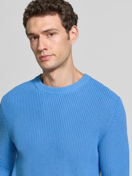 Männermodel trägt Regular Fit Strickpullover aus reiner Baumwolle von MCNEAL in Hellblau, Nahaufnahme Oberkörper, Rundhalsausschnitt, elastische Abschlüsse.