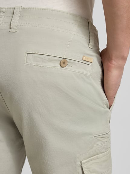 Männermodel trägt Bermudas mit Cargotaschen von bugatti in Beige, Regular-Fit, Gesäßtasche, Nahaufnahme Rückansicht, Bundweite 45 cm, Innenbeinlänge 30 cm.