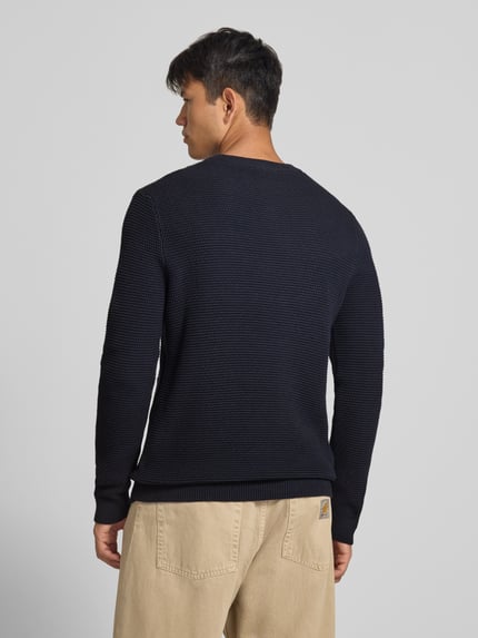 Männermodel trägt Regular Fit Strickpullover aus reiner Baumwolle von REVIEW, dunkle Farbe, gerippte Abschlüsse, Rückenansicht, Ganzkörperansicht Rückansicht.