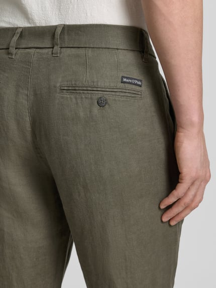 Männermodel trägt Leinenhose Modell 'OSBY JOGGER PLEATS' von Marc O'Polo, efekt: jednolity kolor, krój tapered fit, zakładka w pasie, elastyczny ściągacz, zapięcie na guzik i zamek błyskawiczny, wpuszczane kieszenie, kieszenie z wypustkami z guzikiem, materiał: len, detalaufnahme