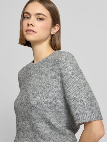 Frauenmodel trägt Strickpullover mit 1/2-Arm und Rundhalsausschnitt von Gina Tricot, grau meliert, Material-Mix mit Lanawoll-Anteil, Ziersteinbesatz, Regular-Fit, Nahaufnahme Oberkörper.