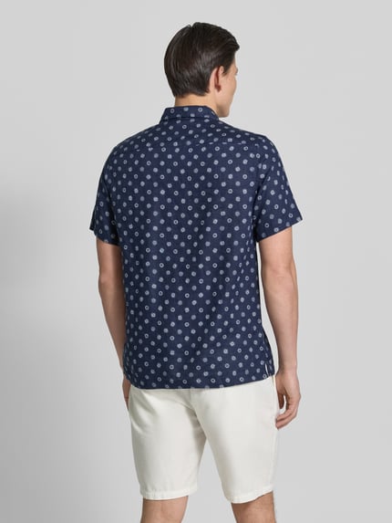 Männermodel trägt Regular Fit Leinenhemd mit Brusttasche von Scotch & Soda, Dunkelblau mit Allover-Motiv-Print, Ganzkörperansicht Rückansicht.