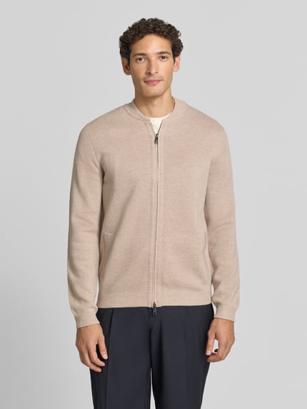 Mężczyzna nosi Slim Fit Strickjacke aus Baumwoll-Mix mit Stehkragen von Christian Berg Men, kolor beżowy, zamek błyskawiczny dwustronny, prążkowane wykończenia, długość tyłu 68 cm, długość rękawów 67 cm, Ganzkörperansicht von vorne