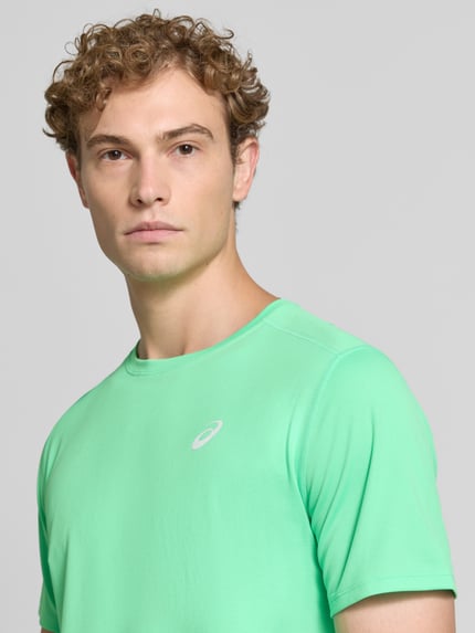 Männermodel trägt T-Shirt mit Logo-Print Modell 'CORE' von ASICS TIGER in Mintgrün, glatte Oberfläche, Nahaufnahme Oberkörper.
