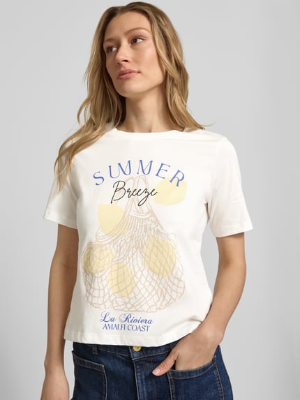 Modelka kobieca nosi T‑Shirt mit Motiv-Print und Rundhalsausschnitt von Christian Berg Woman Selection, czysta bawełna, krój regular fit, nadruk z motywem, dekolt okrągły, długość tyłu w rozmiarze 36: 55 cm, jasne kolory, prosta forma, gładka faktura, zbliżenie górnej części ciała z przodu.