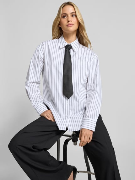 Vrouwenmodel draagt Regular Fit Hemdbluse aus Baumwolle van Anine Bing, puur katoen, regular fit, ritssluiting, zijsplitten, met lange mouwen, ruglengte maat 36: 79 cm, mouwlengte maat 36: 58 cm, wit met zwarte strepen, vooraanzicht bovenlichaam