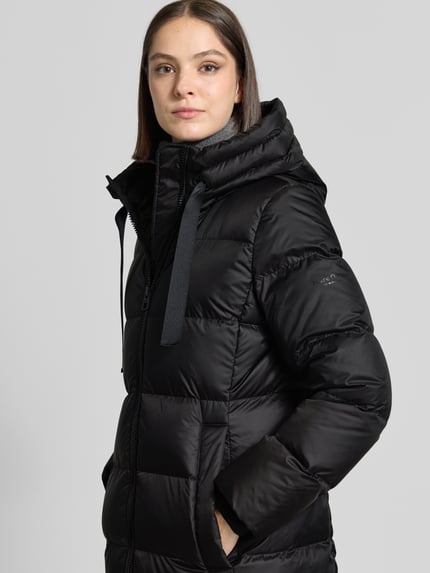 Frauenmodel trägt Regular Fit Daunenmantel mit Label-Print von Marc O'Polo in Schwarz, Oberfläche glatt und gesteppt, Nahaufnahme Oberkörper. Damen Daunenmantel von Marc O'Polo.