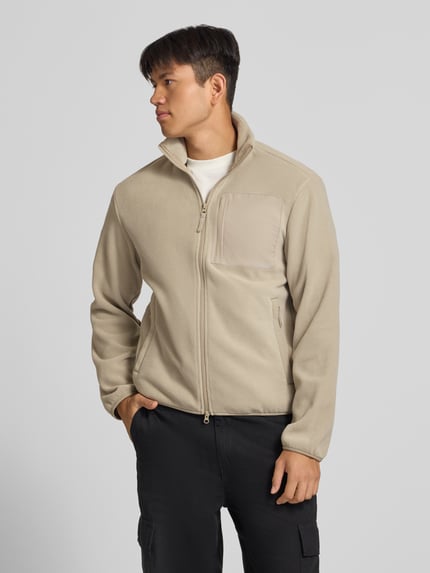 Männermodel trägt Fleecejacke mit Zweiwege-Reißverschluss Modell 'MASON' von JACK & JONES in Beige, Regular Fit, Stehkragen, Logo, Ganzkörperansicht von vorne.