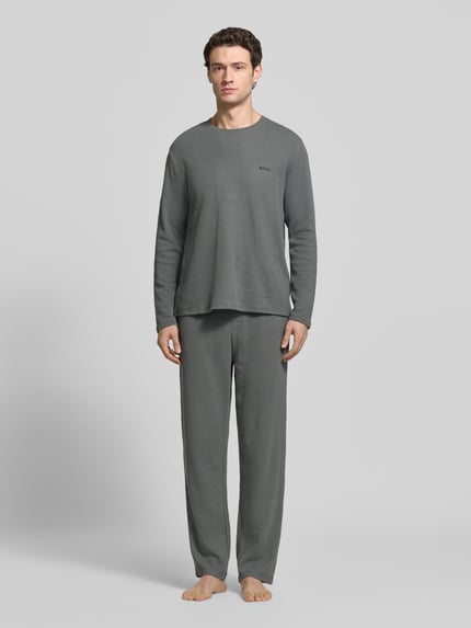 Männermodel trägt Longsleeve mit Logo-Schriftzug von BOSS BLACK, unifarben, Rundhals, langarm, abgerundet, Ganzkörperansicht von vorne.