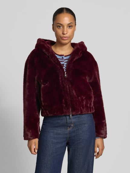 Vrouwenmodel draagt Jacke aus Kunstfell mit Zweiwege-Reißverschluss van Blonde No. 8 in bordeaux, regular fit, kap, vooraanzicht, lengtemaat 50 cm, schouderbreedte 50 cm, borstwijdte 60 cm, mouwlengte 73 cm, detailrijke zachte textuur. Ganzkörperaanzicht van voren.