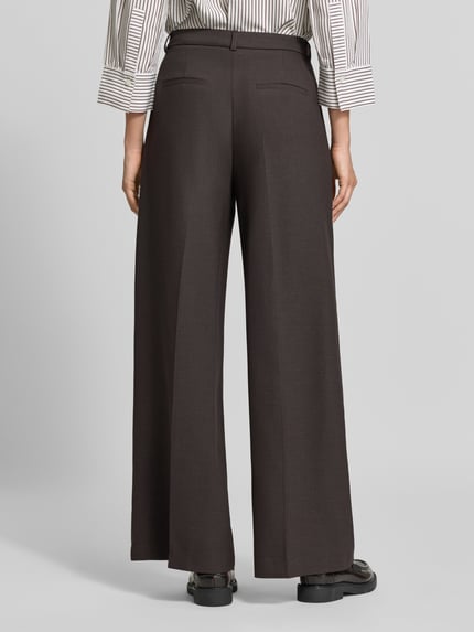Frauenmodel trägt Wide Fit Hose aus Viskose-Mix von comma, dunkelbraun, mit Bundfalten und Gesäßtaschen, Ganzkörperansicht Rückansicht.