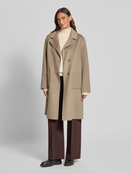 Modelka nosi Regular Fit Mantel aus Woll-Mix mit Reverskragen von Fuchs Schmitt, beżowy kolor, nakładane kieszenie, mieszanka wełny, krój regular fit, kołnierz z połami, listwa z 2 guzikami, długość tyłu w rozmiarze 36: 102 cm, szerokość ramion w rozmiarze 36: 50 cm, szerokość klatki piersiowej w rozmiarze 36: 58 cm, długość rękawów w rozmiarze 36: 65 cm. Widok całej sylwetki od przodu.