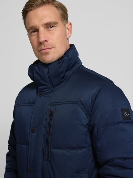Männermodel trägt Regular Fit Steppjacke mit Kapuze von Tom Tailor in Optik: Unifarben mit Stehkragen und Label-Patch, Nahaufnahme Oberkörper.