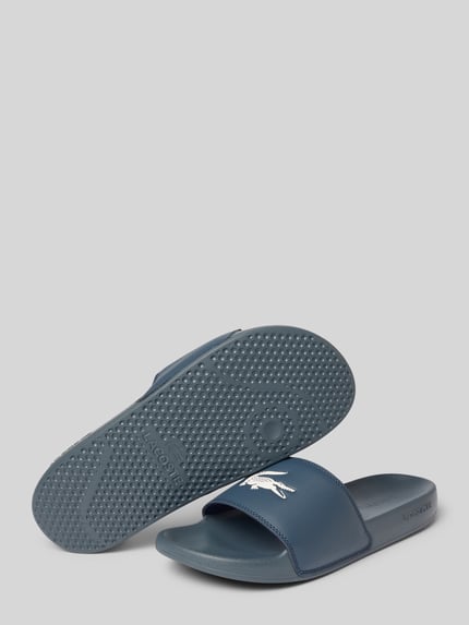 Produktfoto, Badeschuhe mit Logo Print Modell 'SERVE SLIDE' von Lacoste, Optik: Unifarben, Schuhspitze: Abgerundet, Absatzform: Flach, Applikation: Logo-Print, Verschluss: Schlupf/offen, Sohle: Strukturiert, in Dunkelblau.