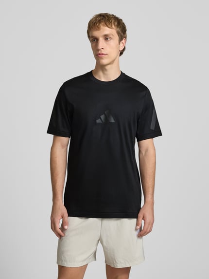 Männermodel trägt Regular Fit T-Shirt aus reiner Baumwolle von adidas Sportswear, Optik: Unifarben, Logo-Print, Rundhals, Kurzarm, Ganzkörperansicht von vorne.