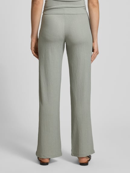 Männermodel trägt strukturierte Pull-on-Hose von REVIEW, materiał z domieszką stretchu, krój wide leg, elastyczny pas, strukturalny wzór, szerokość w rozmiarze S: 36 cm, długość nogawki wewnętrznej w rozmiarze S: 81 cm, widok całej sylwetki od tyłu