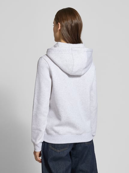 Frauenmodel trägt Regular Fit Sweatjacke aus Baumwoll-Mix von Tommy Jeans in Hellgrau-Melange, Kapuze, lange Ärmel, Ganzkörperansicht Rückansicht.