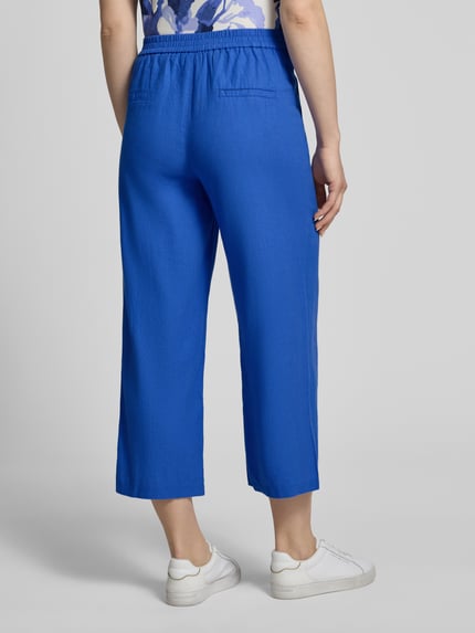 Frauenmodel trägt Leinenhose mit französischen Eingrifftaschen von Betty Barclay im kräftigen Blau, Leinen-Mix mit Viskose-Anteil, Loose-Fit, elastischer Bund mit Haken-Reißverschluss, angedeutete Gesäßleistentaschen, Bundweite 38 cm, Innenbeinlänge 64 cm, Ganzkörperansicht Rückansicht.