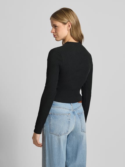 Frauenmodel trägt Cardigan in Ripp-Optik Modell 'CHILL' von Nike in Schwarz mit Skinny-Fit, Stehkragen, Label-Stitching, langärmelig, durchgehende Knopfleiste, Ganzkörperansicht Rückansicht.